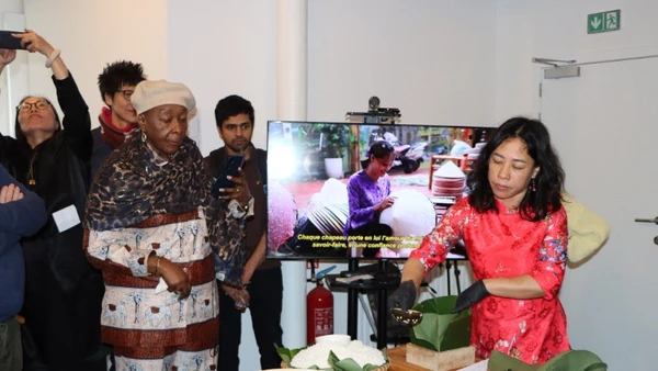 Chị Nguyễn Thị Liên, Việt kiều tại Brussels, giới thiệu cách gói bánh chưng. (Ảnh: HƯƠNG GIANG/TTXVN)