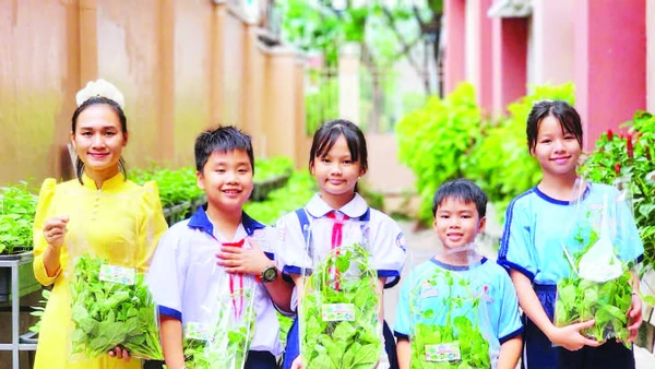 Cô trò Trường tiểu học Đặng Trần Côn (phường Vĩnh Hội) thu hoạch rau tại vườn.