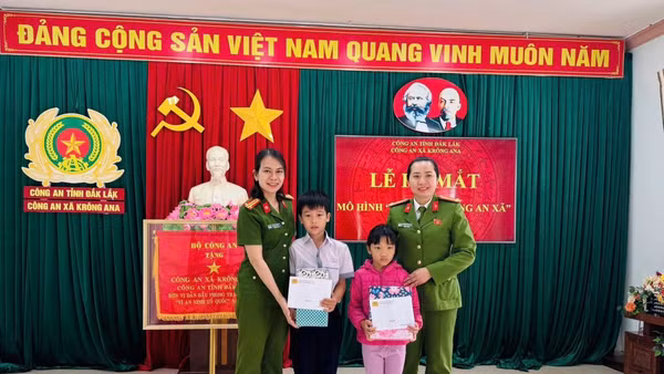 Đại diện Công an xã Krông Ana tặng quà cho con nuôi Đặng Hải Đăng và Hoàng Bảo Ngọc.