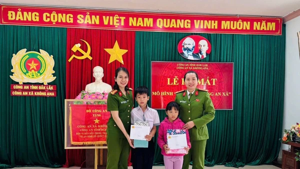 Đại diện Công an xã Krông Ana tặng quà cho con nuôi Đặng Hải Đăng và Hoàng Bảo Ngọc.