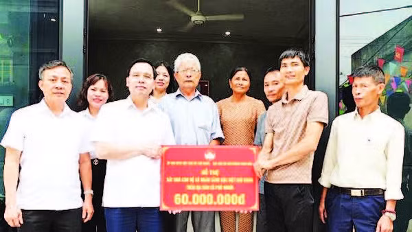 Bí thư Đảng ủy xã Phú Nghĩa Trịnh Tiến Tường (bên trái) trao biển hỗ trợ nhà ở cho hộ có hoàn cảnh khó khăn trên địa bàn.