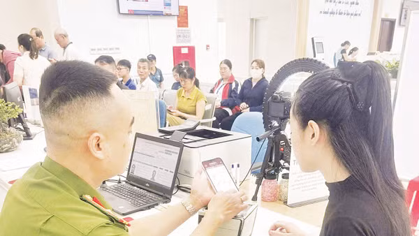 Cán bộ Phòng Cảnh sát QLHC về TTXH hướng dẫn người dân tích hợp tài khoản an sinh xã hội trên VNeID. 