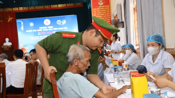 Cán bộ công an xã và nhân viên y tế hướng dẫn, hỗ trợ người dân đến khám sức khỏe.