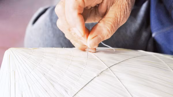Người dân làng Sai Nga tỉ mỉ hướng dẫn du khách tập khâu nón.