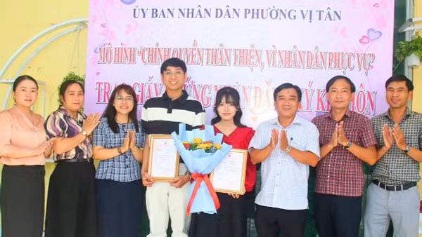 Lãnh đạo Ủy ban nhân dân phường và Trung tâm Phục vụ hành chính công phường Vị Tân trao giấy chứng nhận kết hôn và tặng hoa chúc mừng cặp đôi.