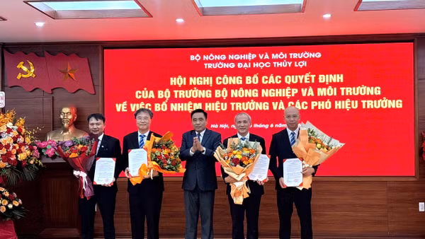 Thứ trưởng Nông nghiệp và Môi trường Nguyễn Quốc Trị trao quyết định và tặng hoa cho Ban giám hiệu Trường đại học Thủy lợi. 