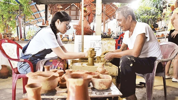 Du khách trải nghiệm làm đồ gốm khi tới thăm làng Thanh Hà.