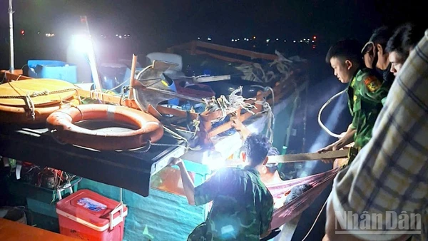 Cán bộ, chiến sĩ Đồn Biên phòng Hòn Chuối hỗ trợ đưa ông Đạt xuống tàu vào bờ tiếp tục cấp cứu, điều trị.