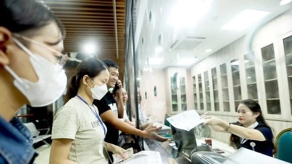 Người dân nộp tiền khám sức khỏe tại Bệnh viện Bạch Mai, Hà Nội. (Ảnh NGUYỄN KHÁNH)