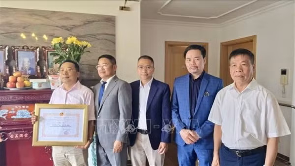 Tham tán Công sứ Chu Tuấn Đức (đứng giữa), Chủ tịch Hội Cựu chiến binh Việt Nam tại Cộng hòa liên bang Đức trao giấy khen, tri ân công lao của gia đình ông Lê Đình Bính có người thân là liệt sĩ. (Ảnh: PHƯƠNG HOA/PV TTXVN TẠI ĐỨC)