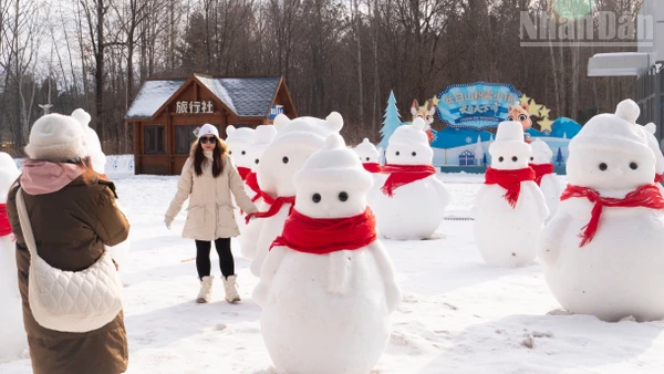 Du khách chụp ảnh check-in với người tuyết bên ngoài ga tàu cao tốc Trường Bạch Sơn.