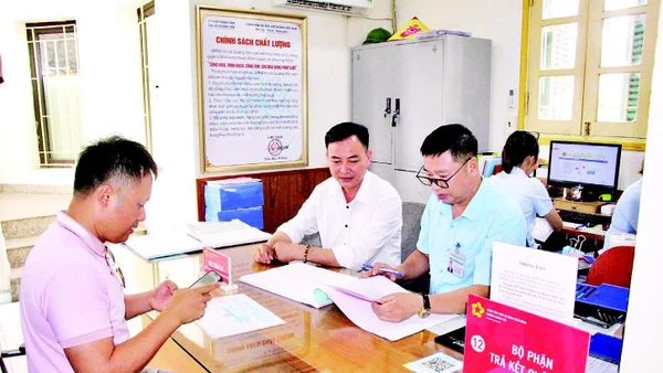 Cán bộ Trung tâm Phục vụ hành chính công phường Quảng Yên (tỉnh Quảng Ninh) hỗ trợ người dân làm thủ tục hành chính. (Ảnh QUANG THỌ)