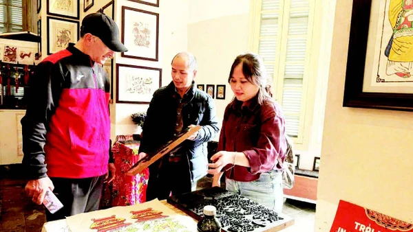 Võ Ca Dao hướng dẫn cho du khách nước ngoài trải nghiệm in tranh mộc bản.