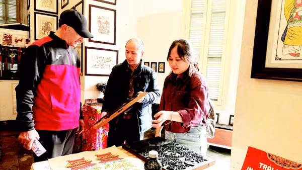 Võ Ca Dao hướng dẫn cho du khách nước ngoài trải nghiệm in tranh mộc bản.
