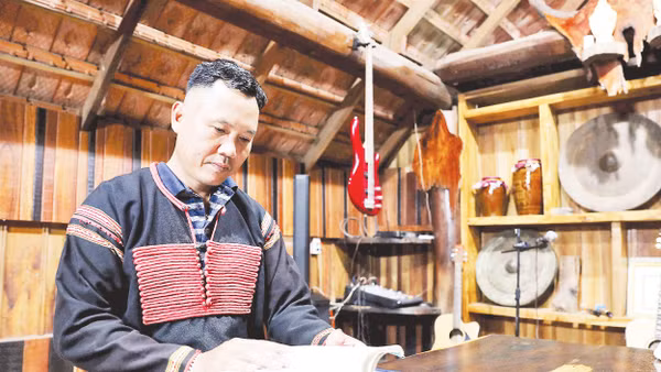 Nghệ nhân Ama Nhiên nghiên cứu các tài liệu sử thi Tây Nguyên trong căn nhà dài của mình. Ảnh: Anh Quân 