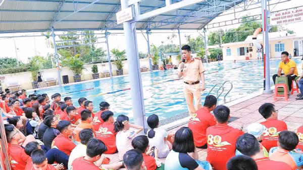 Cán bộ công an tuyên truyền về kỹ năng phòng, chống đuối nước cho trẻ em tại khu vực bể bơi.