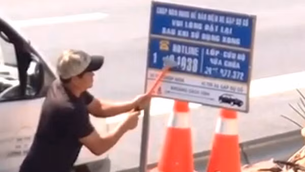 Đối tượng sử dụng dụng cụ cạo sơn để cạo thông tin các số điện thoại hotline và số điện thoại cứu hộ, sửa chữa phương tiện được dán trên biển báo thông tin cứu hộ bị ghi lại hình ảnh. 