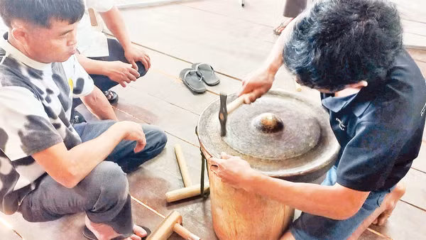 Các học viên thực hành chỉnh âm cồng chiêng tại lớp tập huấn do nhà nghiên cứu Bùi Trọng Hiền hướng dẫn. 