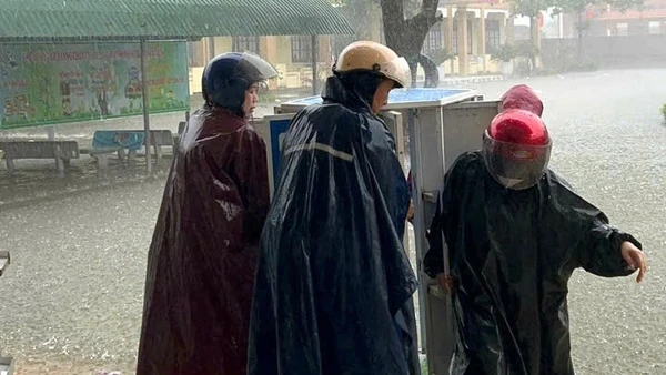 Giáo viên ở xã Quảng Trạch, Quảng Trị, di chuyển tài sản lên cao tránh hư hỏng khi nước lũ đã tràn vào sân trường hôm 31/10. (Ảnh: HƯƠNG GIANG)