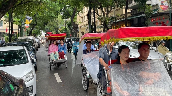 Du khách nước ngoài trên phố Tràng Thi (Hà Nội) ngày mưa. (Ảnh minh họa: Đ.T)