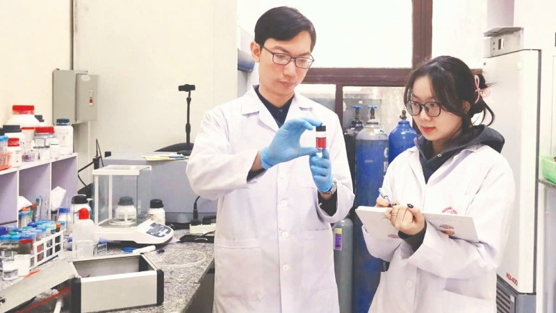 Tiến sĩ Nguyễn Nhật Linh hướng dẫn sinh viên kiểm tra mẫu sản phẩm hạt nano vàng thu được từ quá trình tổng hợp plasma. (Ảnh: MINH ĐỨC)