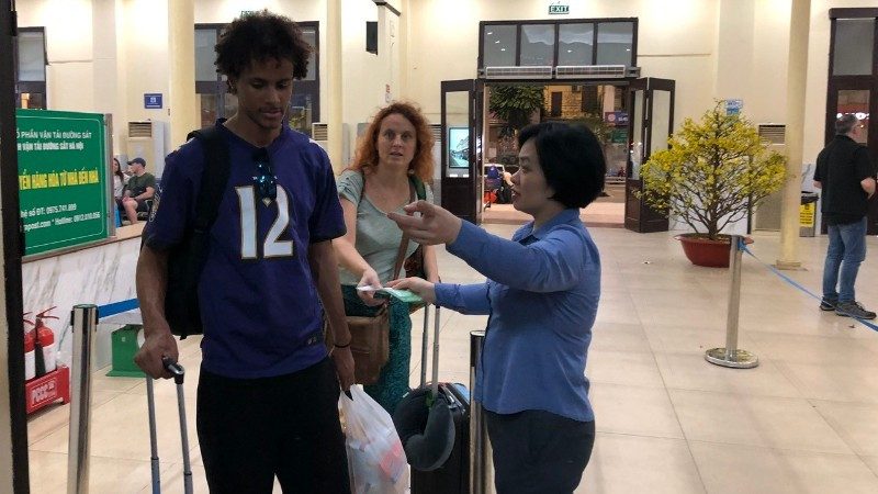 Nhân viên khách vận hướng dẫn hành khách vào ga đi tàu.