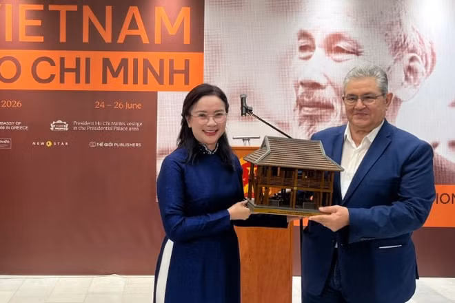 Giám đốc Khu Di tích Chủ tịch Hồ Chí Minh tại Phủ Chủ tịch Lê Thị Phượng trao tặng Tổng Bí thư Đảng Cộng sản Hy Lạp Dimitris Koutsoumpas mô hình Nhà sàn Bác Hồ. (Ảnh: Ban tổ chức)