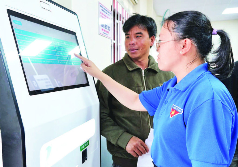 Thanh niên hỗ trợ người dân lấy số thứ tự tại ki-ốt. 2.jpg
