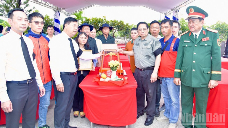 Thủ tướng Phạm Minh Chính động viên thân nhân gia đình liệt sĩ Ngô Văn Liên nhận bàn giao hài cốt liệt sĩ tại buổi lễ để an táng tại quê nhà. (Ảnh: THANH GIANG) ndo_br_a9-1346.jpg