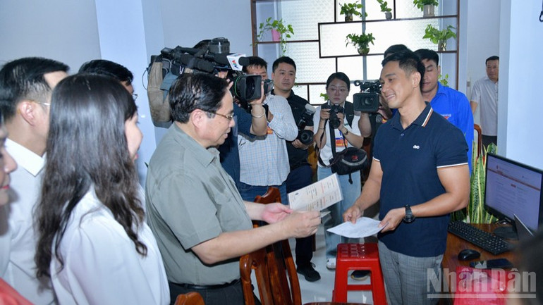 Thủ tướng Phạm Minh Chính hỏi thăm một người dân đến làm thủ tục hành chính tại Trung tâm Phục vụ hành chính công ở phường Thới Sơn. (Ảnh: THANH GIANG) ndo_br_ab2-9330.jpg