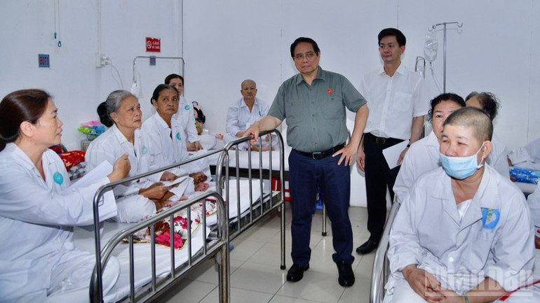Prime Minister Pham Minh Chinh kindly talks and asks about a patient undergoing cancer treatment. (Photo: Thanh Giang) ndo_br_a12-2906.jpg