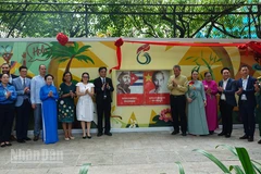 Các đại biểu chụp ảnh lưu niệm bên bức tranh vẽ tường trong buổi lễ khánh thành. (Ảnh: LINH BẢO).