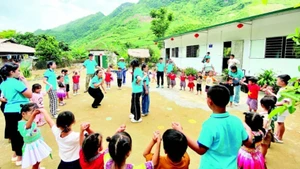 Các thành viên dự án “Đông ấm cho trẻ em vùng cao” cùng học sinh điểm trường Pa Phang 2, Trường mầm non Phìn Hồ (huyện Sìn Hồ, Lai Châu) bên hai lớp học mới khánh thành dịp Quốc tế Thiếu nhi. (Ảnh: PHONG CHƯƠNG)