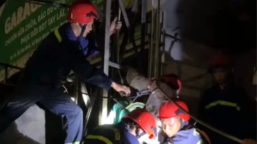 Lực lượng cứu hộ dùng dây, đai đưa ông T từ trên bảng quảng cáo xuống đất.