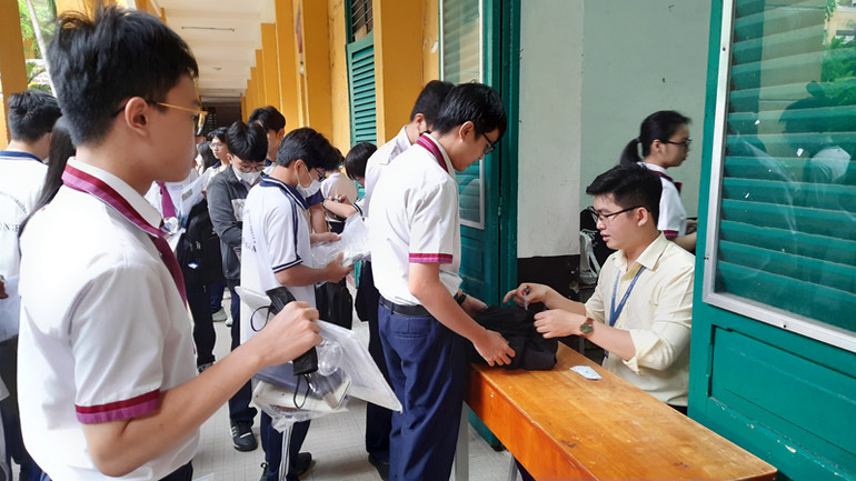 Các thí sinh làm thủ tục gửi đồ ở khu vực giữ vật dụng cho thí sinh tại điểm thi Trường trung học phổ thông Trưng Vương, quận 1.