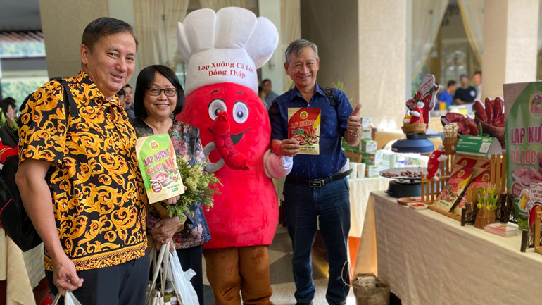 Du khách thích thú với sản phẩm lạp xưởng cá lóc và lạp xưởng cua đồng của chị Dương Thị Hồng Chuyên.