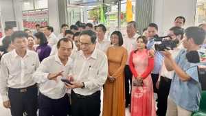 Chủ tịch Quốc hội trao đổi với cán bộ trung tâm giải quyết thủ tục hành chính tại phường Phú Lợi về cách thức ứng dụng, khai thác trí tuệ nhân tạo trong xử lý công việc.