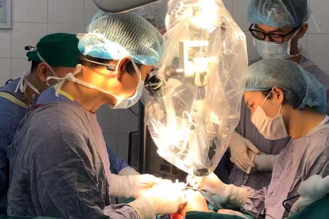 Ê-kíp mổ thực hiện vi phẫu nối lại ngón tay cho người bệnh với kính hiển vi.