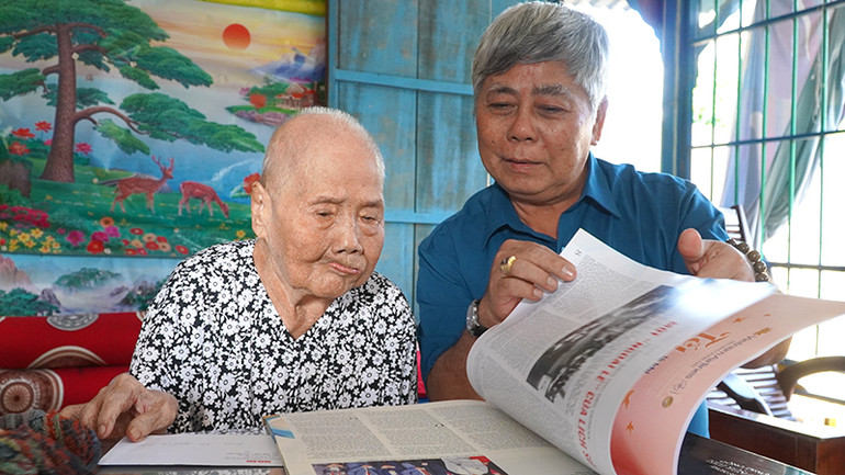 Đồng chí Dương Hồng Lâm, Phó Trưởng Cơ quan Thường trực Báo Nhân Dân tại Cần Thơ cùng mẹ Việt Nam Anh hùng Nguyễn Thị Dãnh đọc báo xuân Nhân Dân 2024. (Ảnh: HỮU NGHĨA)