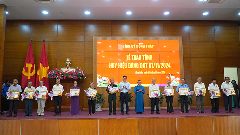 Phó Bí thư Tỉnh ủy, Chủ tịch Ủy ban nhân dân tỉnh Đồng Tháp Phạm Thiện Nghĩa trao Huy hiệu 55 năm tuổi Đảng; Trưởng Ban Tuyên giáo Tỉnh ủy Đồng Tháp Lê Thị Kim Loan tặng hoa chúc mừng các đảng viên. (Ảnh: HỮU NGHĨA)