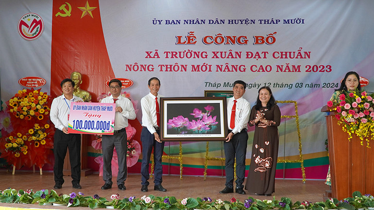 Huyện ủy, Ủy ban nhân dân huyện Tháp Mười tặng quà lưu niệm và 100 triệu đồng cho xã Trường Xuân để thực hiện công trình tại địa phương. (Ảnh: HỮU NGHĨA)