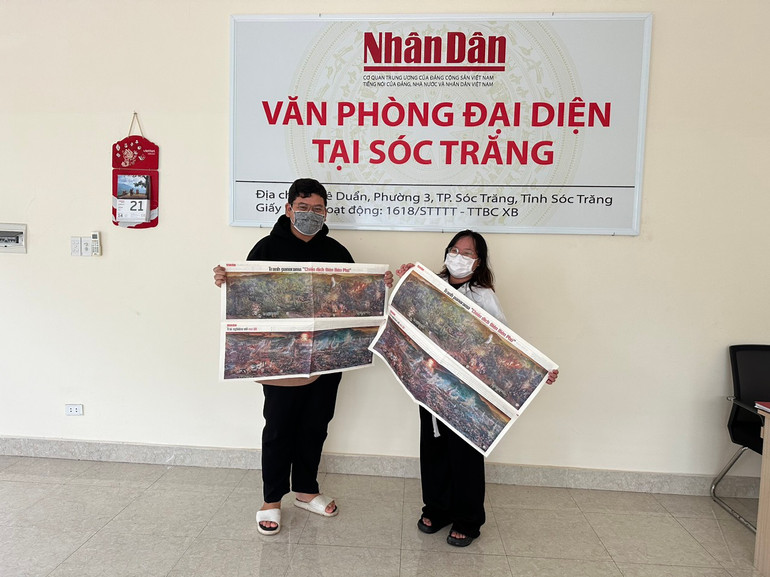 Hai bạn sinh viên không giấu nổi niềm vui khi nhận được phụ san tranh panorama Chiến dịch Điện Biên Phủ tại Văn phòng đại diện Báo Nhân Dân ở Sóc Trăng.