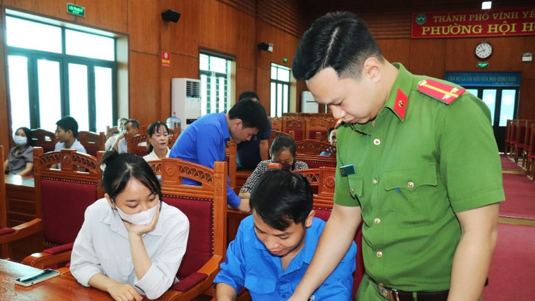 Thanh niên thành phố Vĩnh Yên hướng dẫn người dân sử dụng ứng dụng VneID. (Ảnh: Dương Hà)