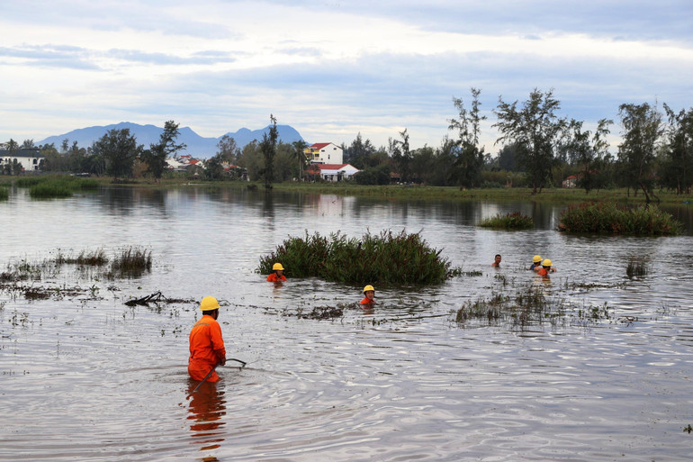 Công nhân dầm mình trong nước để khắc phục sự cố lưới điện ở Hội An, Quảng Nam. (Ảnh: Hoàng Thạch)