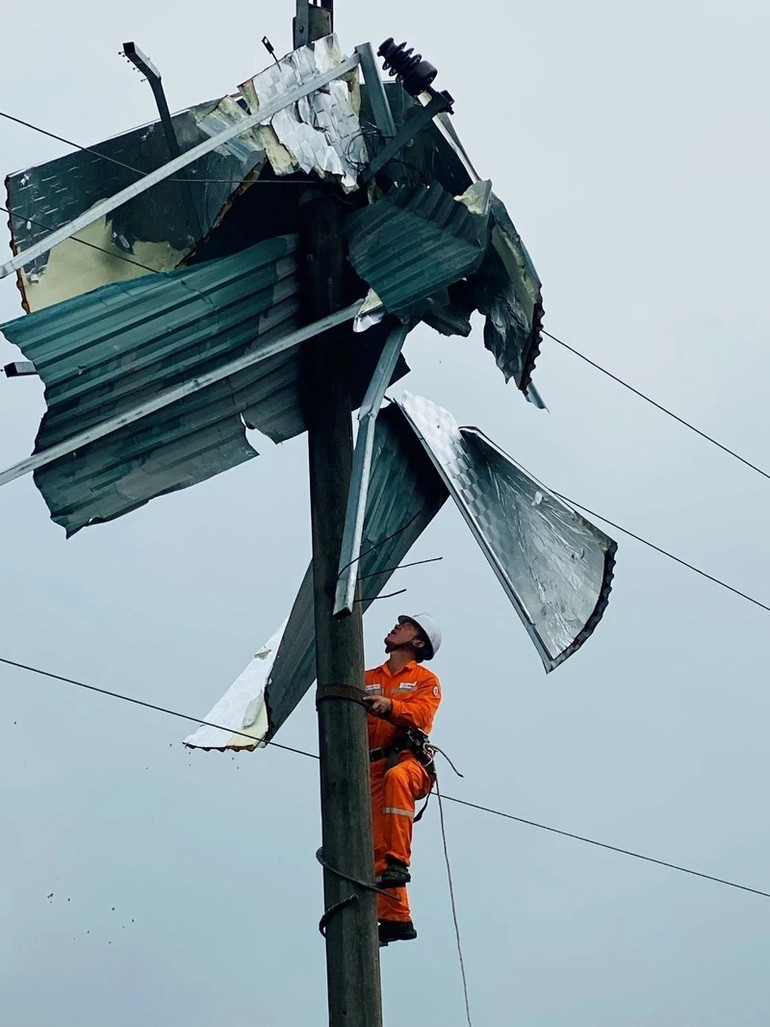 Công nhân Điện lực Bát Xát (Lào Cai) gỡ mái tôn khỏi cột điện.