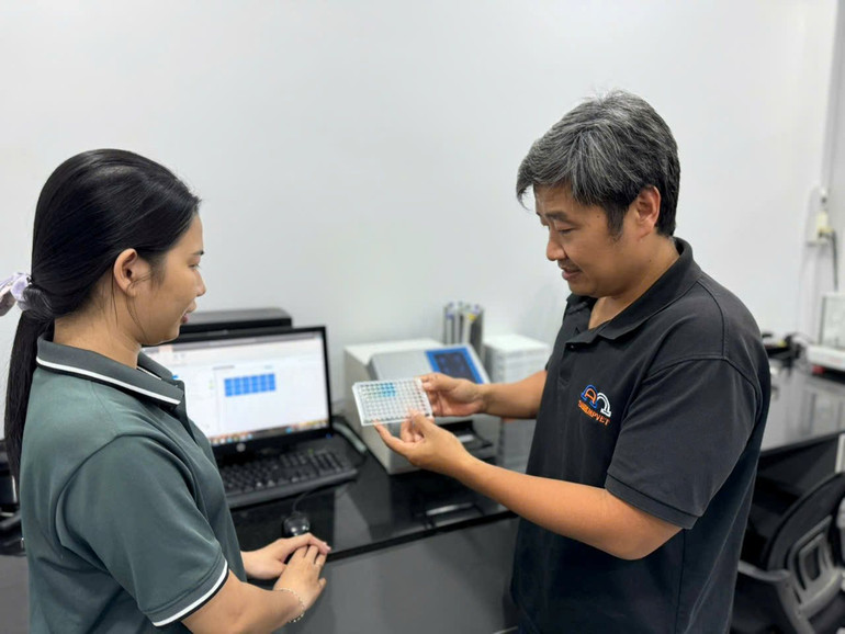 Tiến sĩ Trần Hữu Lộc (bên phải) trao đổi với cộng sự về kết quả phân tích thí nghiệm. (Ảnh THỤC KHUÊ)