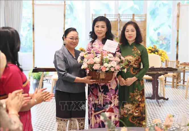 Đại sứ Lào tại Việt Nam Khamphao Ernthavanh (bên trái) và Chủ tịch danh dự của Nhóm Phụ nữ Cộng đồng ASEAN Vũ Thị Bích Ngọc (bên phải) tặng hoa chúc mừng Phu nhân Tổng Bí thư, Chủ tịch nước Ngô Phương Ly. (Ảnh: An Đăng/TTXVN)