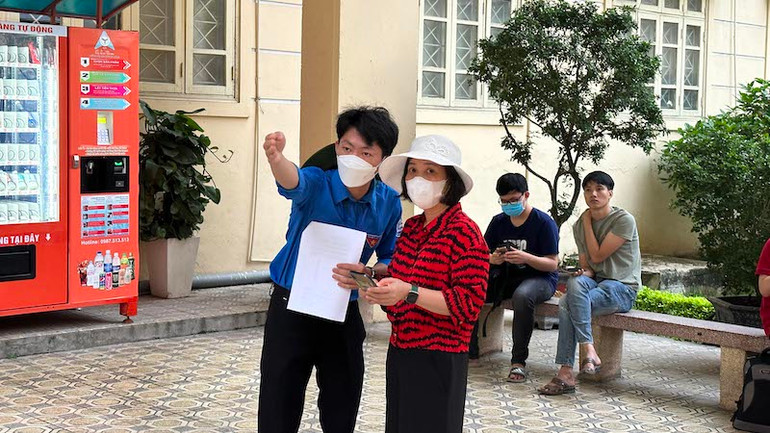 Sinh viên tình nguyện hướng dẫn phụ huynh di chuyển đến phòng chờ thí sinh. (Ảnh: THÚY QUỲNH)
