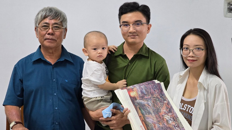 Một gia đình trẻ bế cả con trai 16 tháng tuổi đến nhận tranh panorama Chiến thắng Điện Biên Phủ.