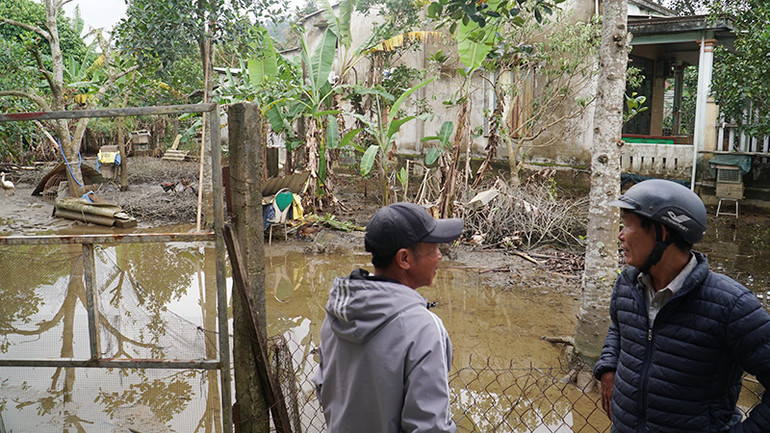 Sau khi tạo kênh thoát nước, vườn nhà chị Vân đã bắt đầu rút nước. Trưởng thôn Nguyễn Văn Bảo (phải) đến thăm nhà chị Vân.